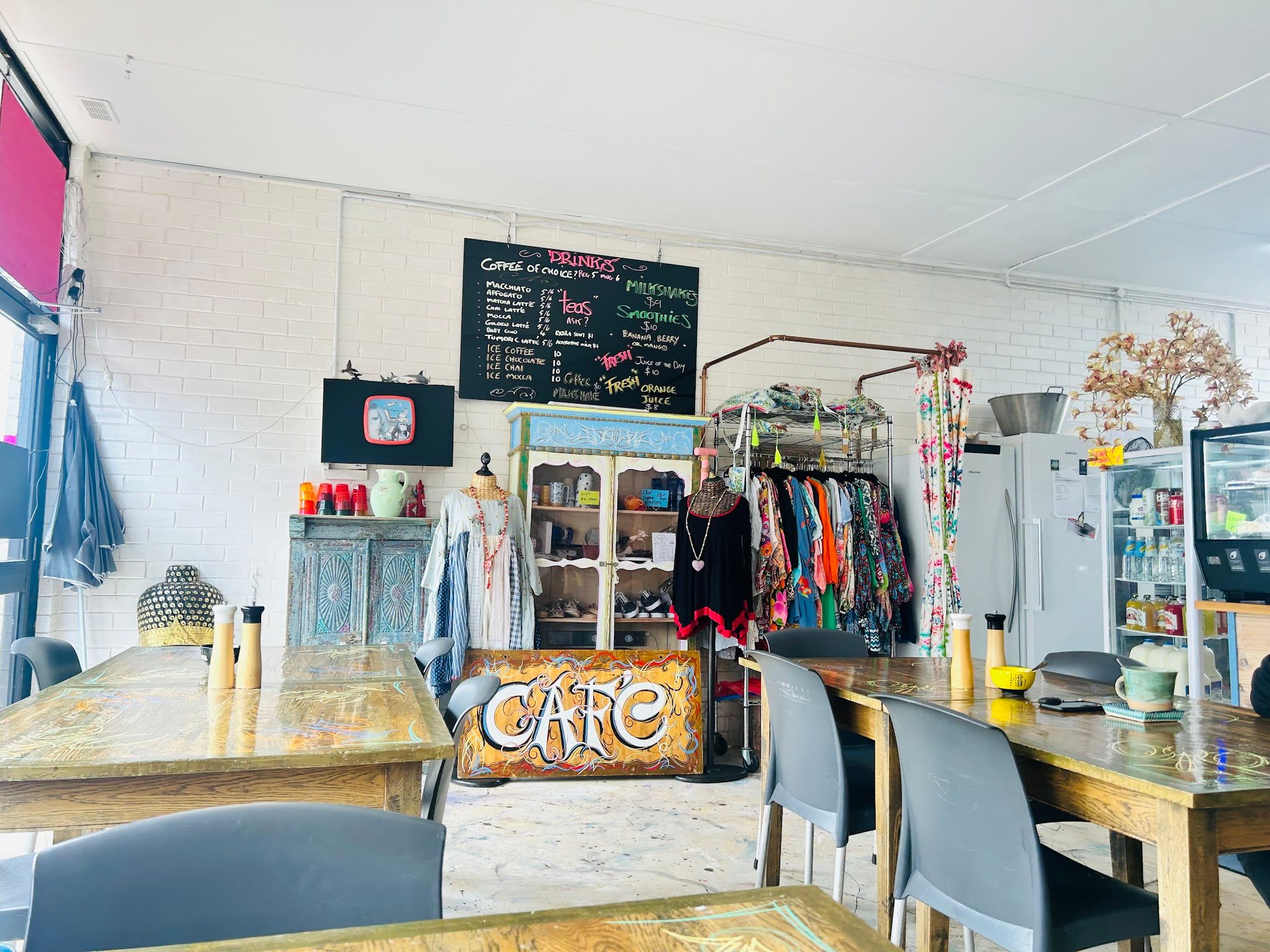 Cafe Sari interior with chalkboard menu, clothing rack, and eclectic timber furniture