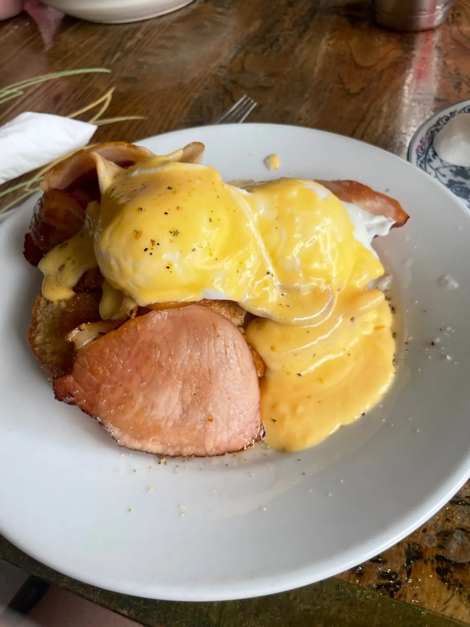 Eggs Benedict with poached eggs, bacon and hollandaise sauce on sourdough toast on a white plate