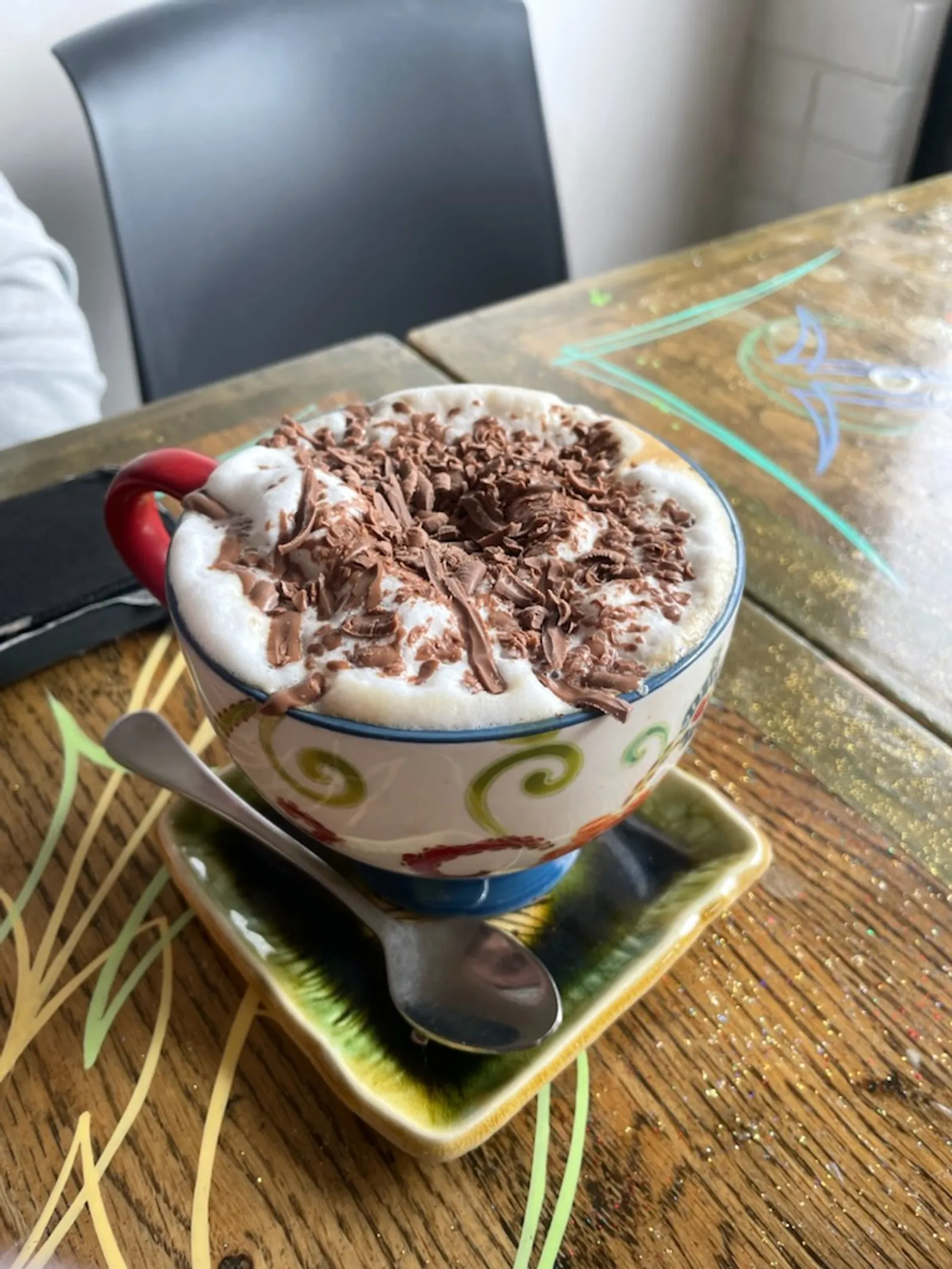 Hot chocolate in a colourful ceramic folk-art mug with whipped cream and chocolate
