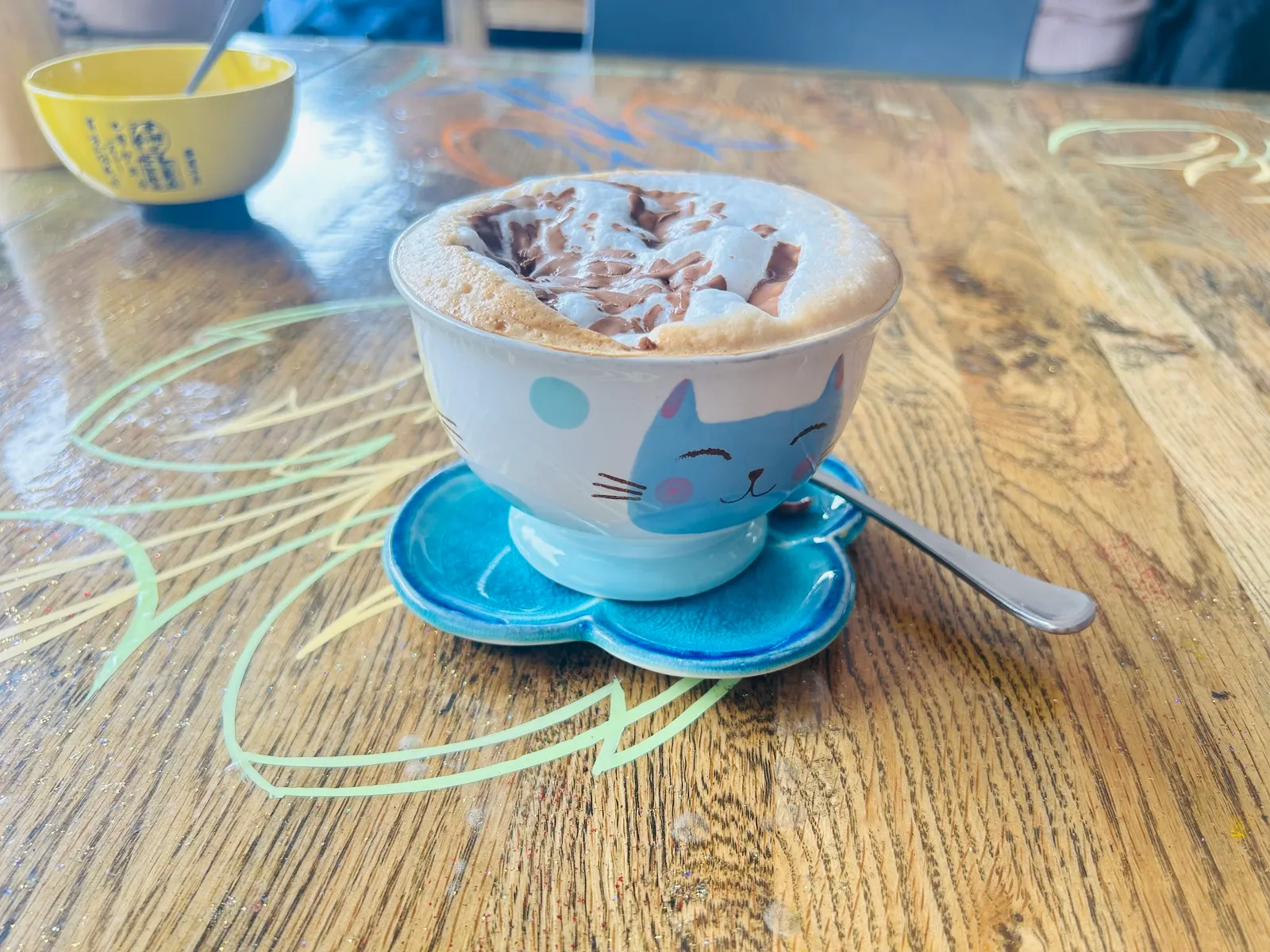 Latte in a cat-face novelty bowl mug on a flower-shaped blue saucer at Cafe Sari