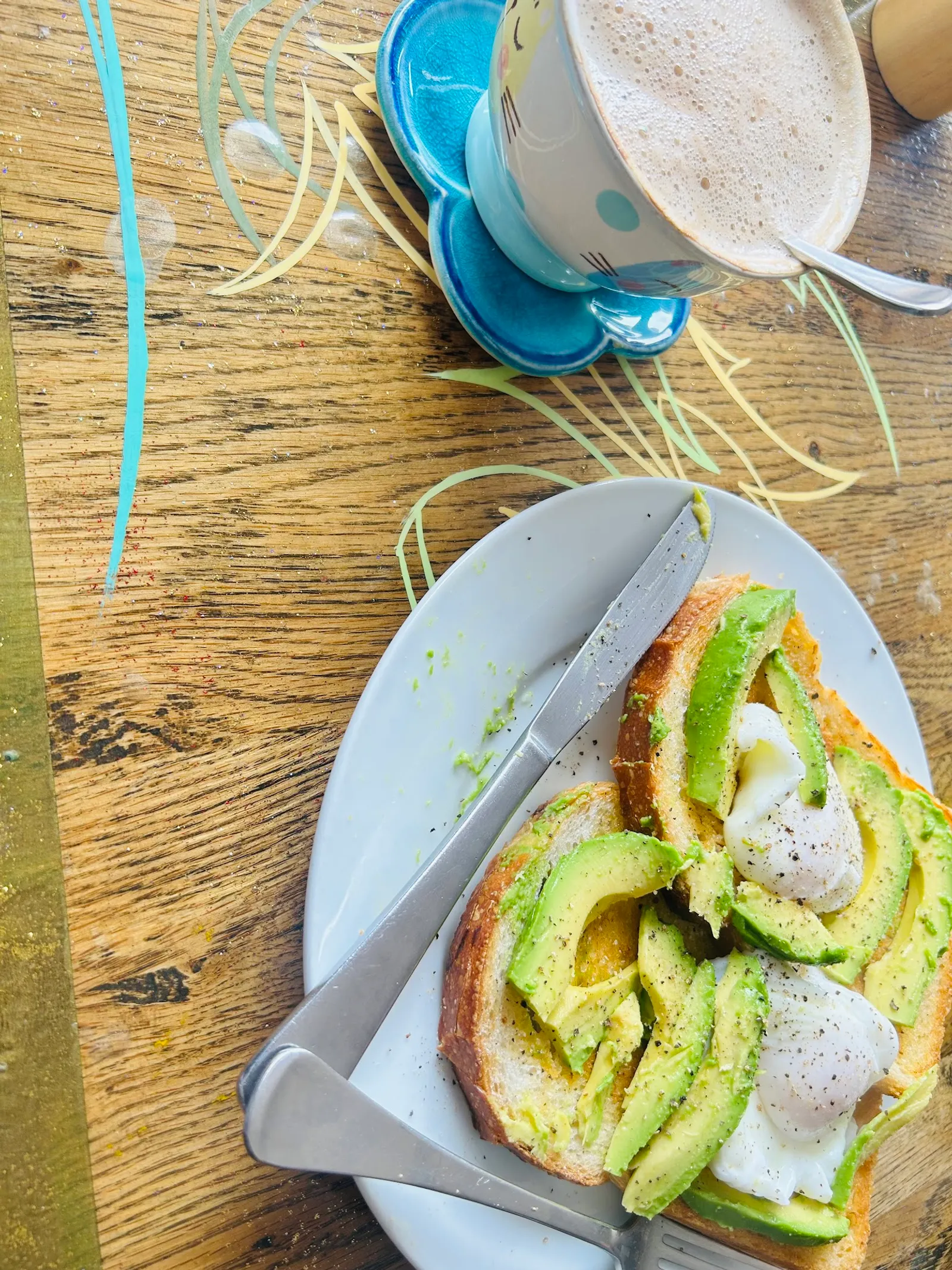 Avocado toast with poached egg and a novelty cat-face latte mug at Cafe Sari
