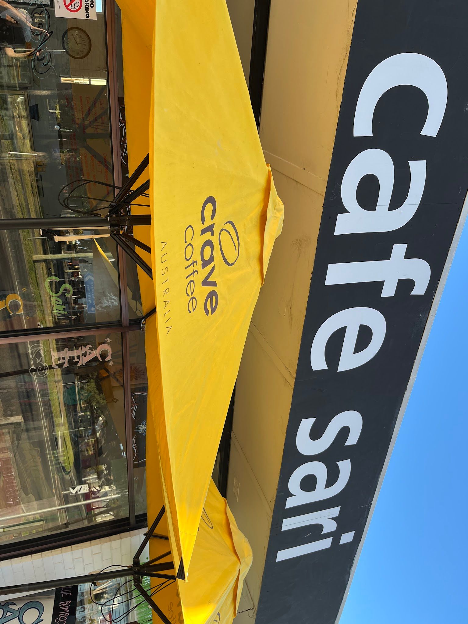 Cafe Sari storefront on Church Street Cowes with black signage and yellow coffee umbrella